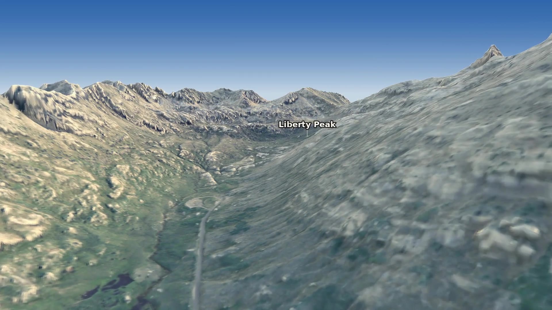 Looking up Lamoille Canyon toward its head, with craggy grey ridges, green avalanche chutes and the canyon floor curving south