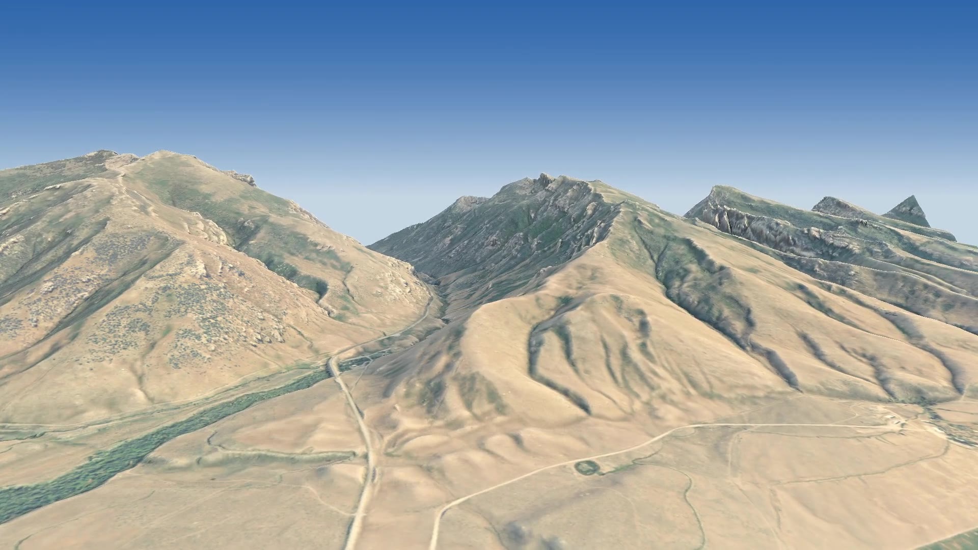 High over the sagebrush of the Lamoille valley, looking south-east at the front of the Ruby Mountains, with the Lamoille Canyon road winding toward the canyon mouth