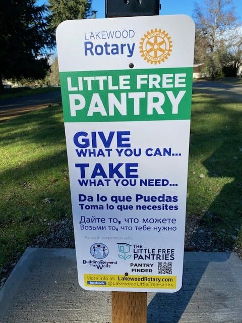 Lakewood Rotary Little Free Pantry sign — Give what you can, Take what you need — in English, Spanish, and Russian
